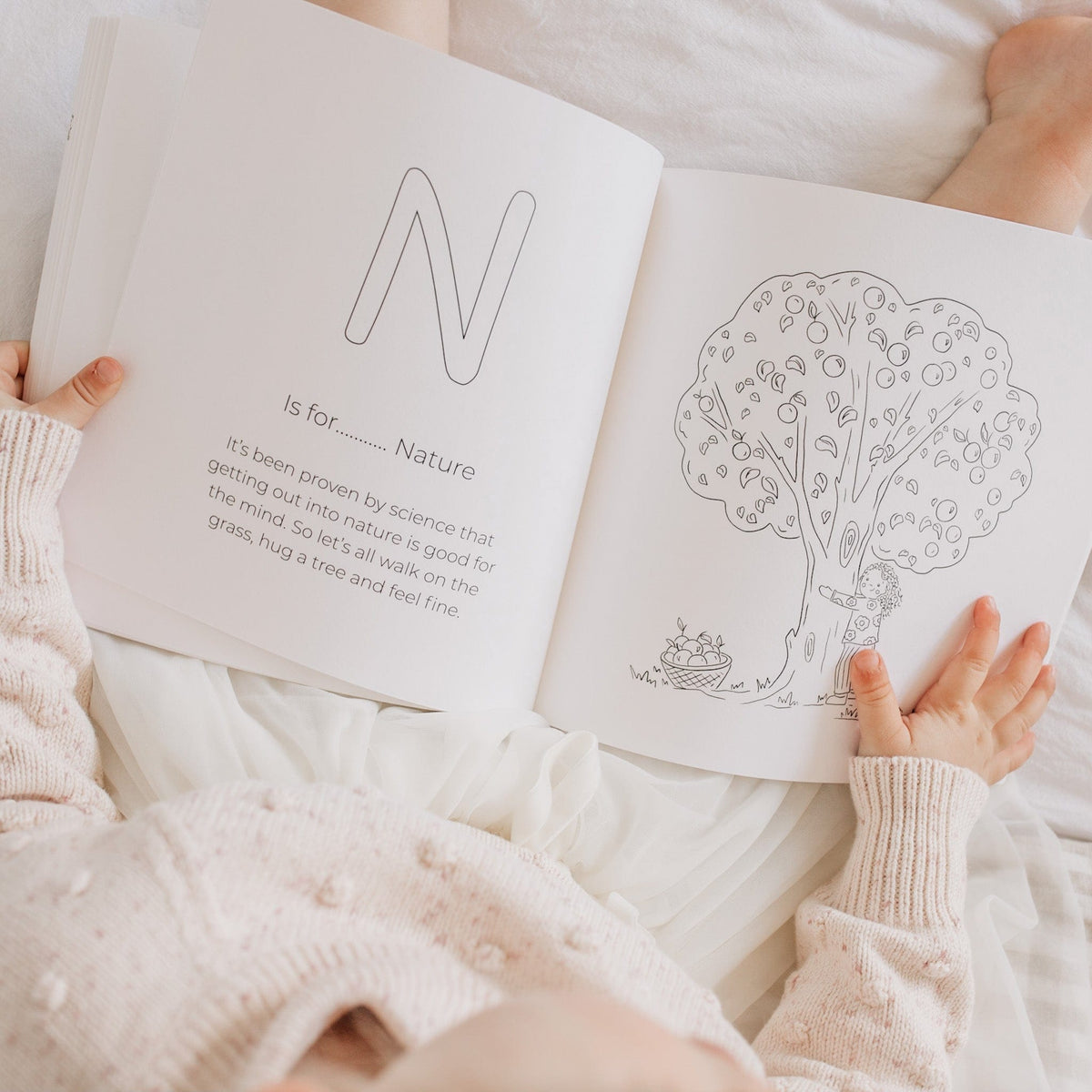 Child holding the ABCs of Mindfulness book open at N is for Nature