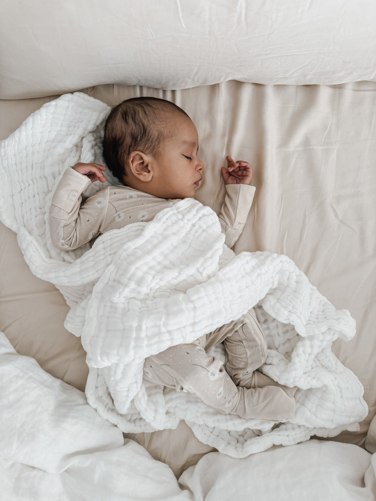 Luna + Luca cotton gauze baby blanket in white, over a newborn