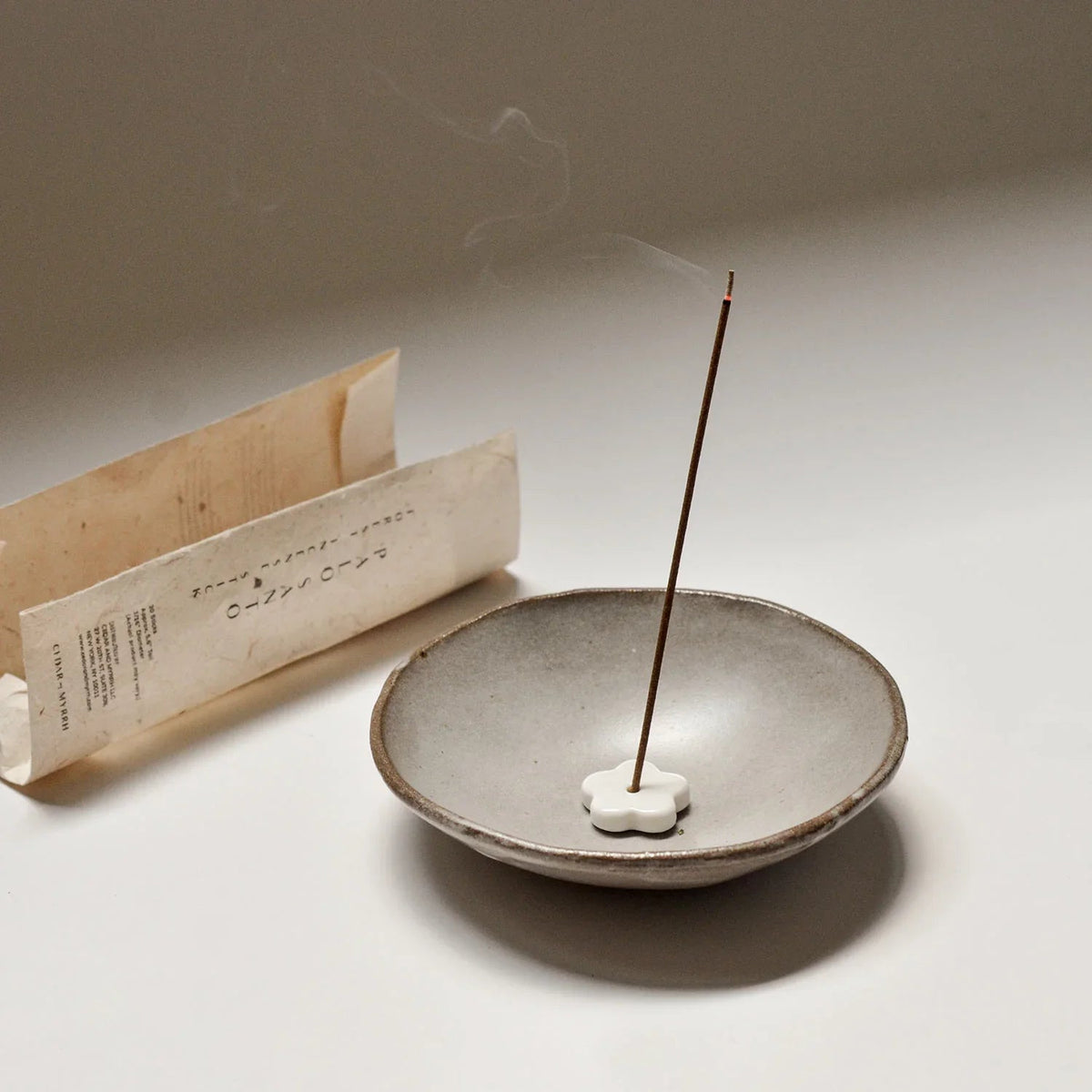 A palo santo incense stick burning in its ceramic holder
